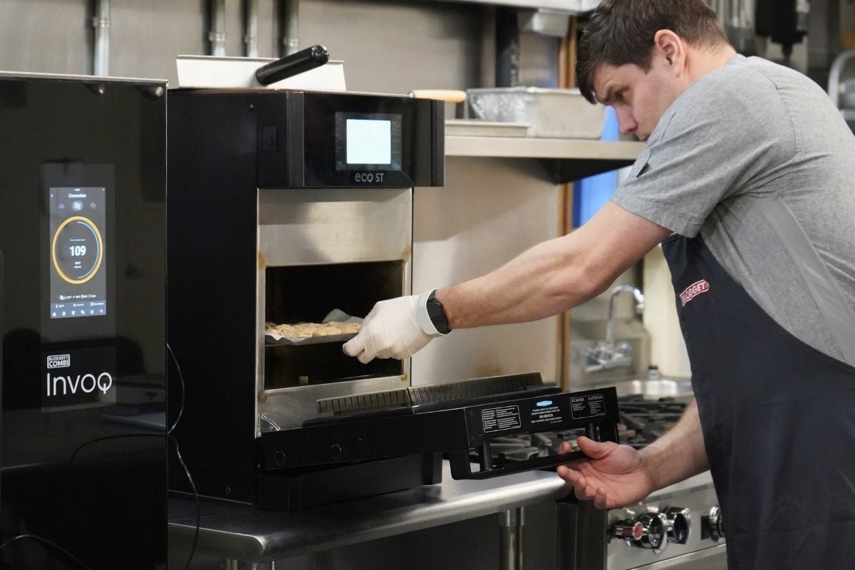 Chef testing a rapid cook oven during a live equipment demo at the One Source Reps Test Kitchen in the Philadelphia region.
