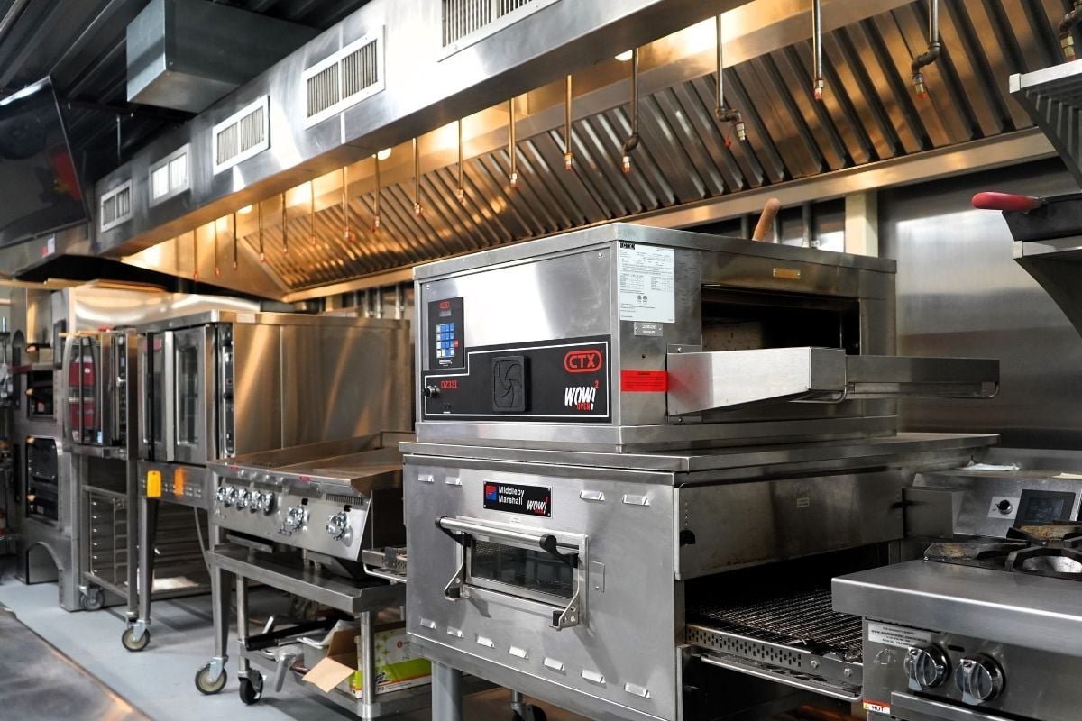 Commercial kitchen line inside the One Source Reps Test Kitchen showcasing high-volume equipment and workflow layouts.